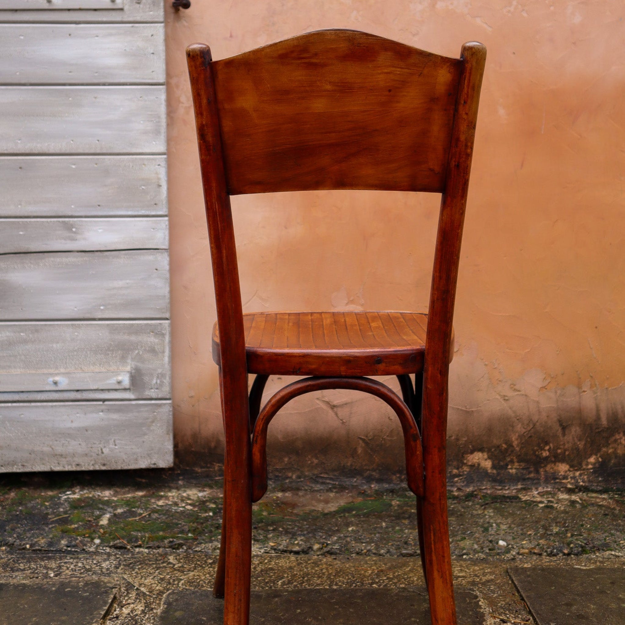 Wooden chair against a textured wall and wooden door.