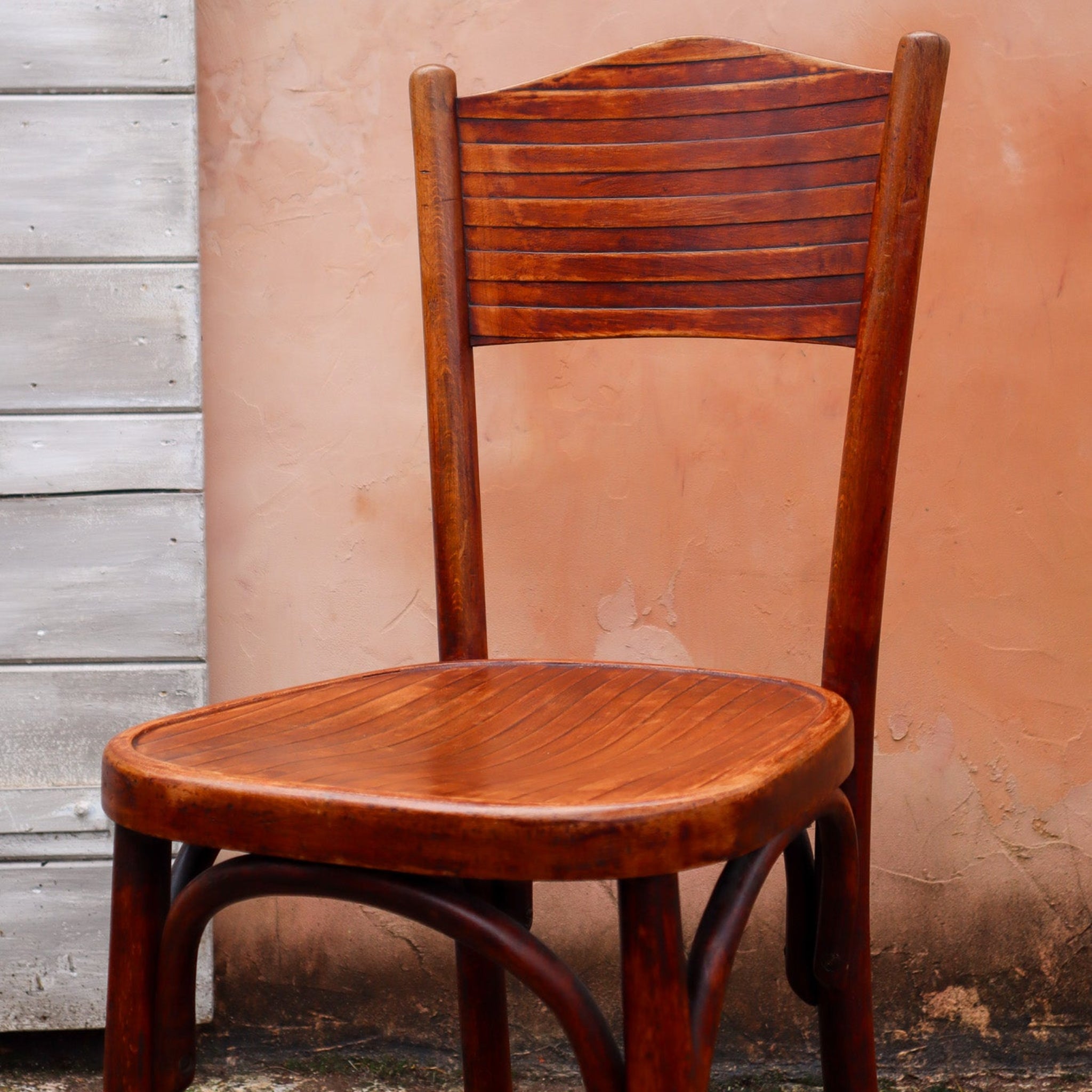 Wooden chair against a textured wall with wooden paneling.